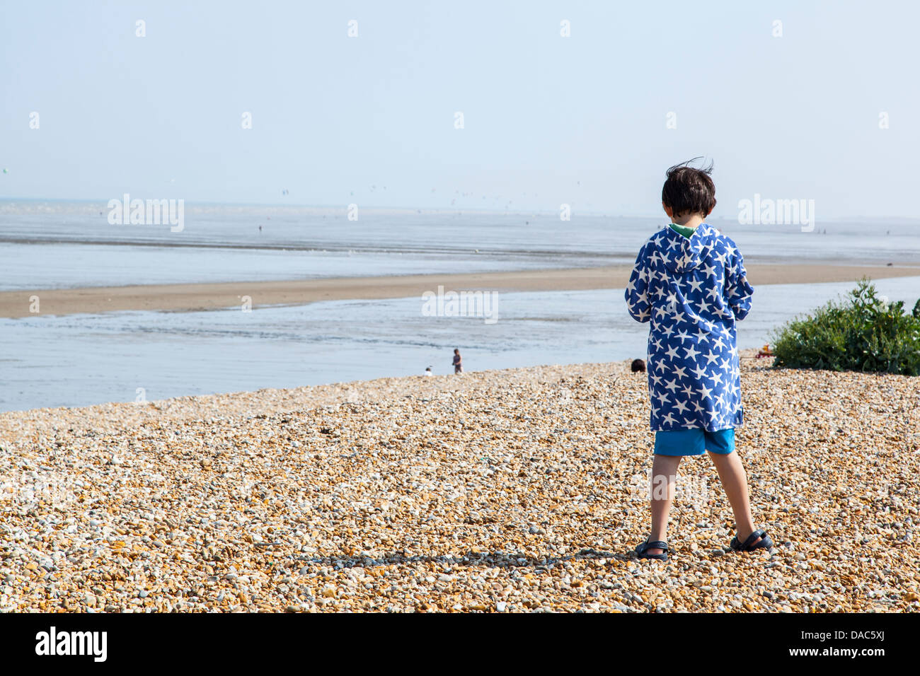 Junge stand am Strand, blaue Jacke mit weißem Muster, Meer Strand mit jungen stehen, mit Blick auf den Strand Stockfoto