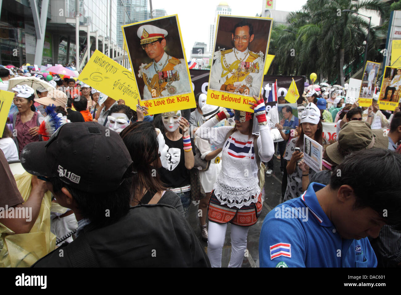 Guy Fawkes weiße Masken Demonstranten halten Porträt von Thailands König Bhumibol Adulyadej und Königin Sirikit bei protest Stockfoto