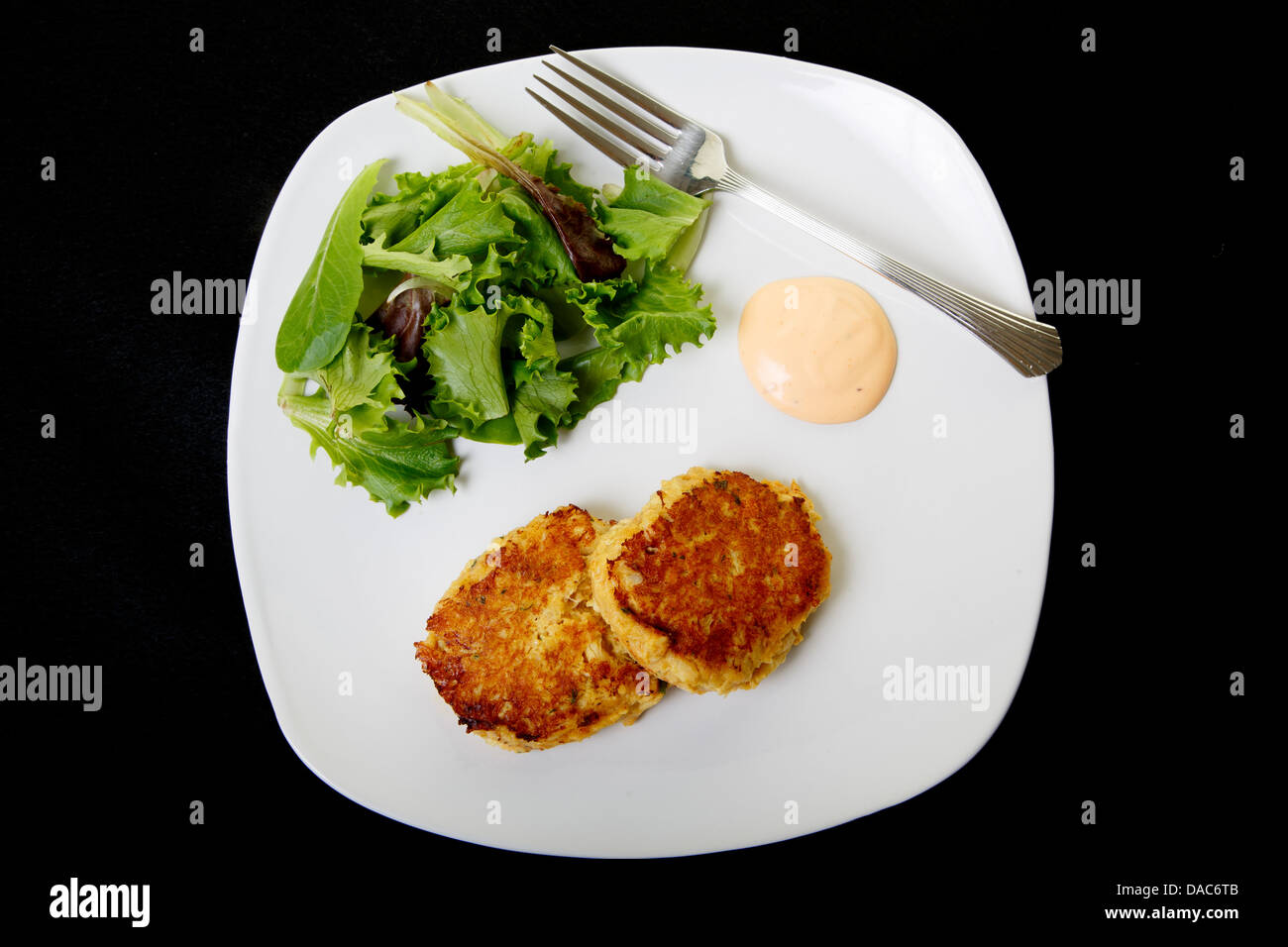 Frische Krabbenkuchen auf einem weißen Teller mit Sauce und einen frischen Salat der grünen Feld Stockfoto