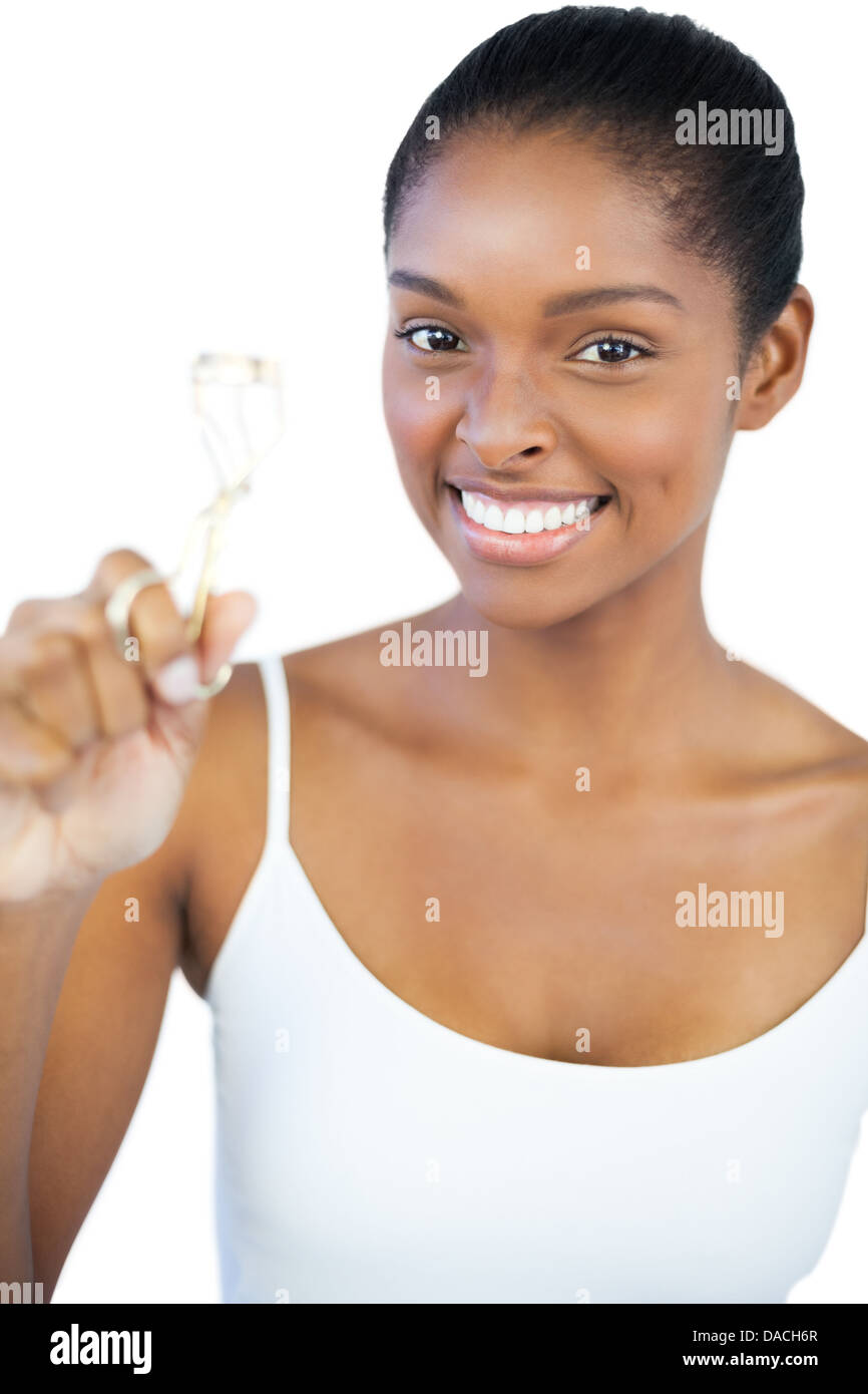 Lächelnde Frau betrachten ihre Wimpernzange Stockfoto