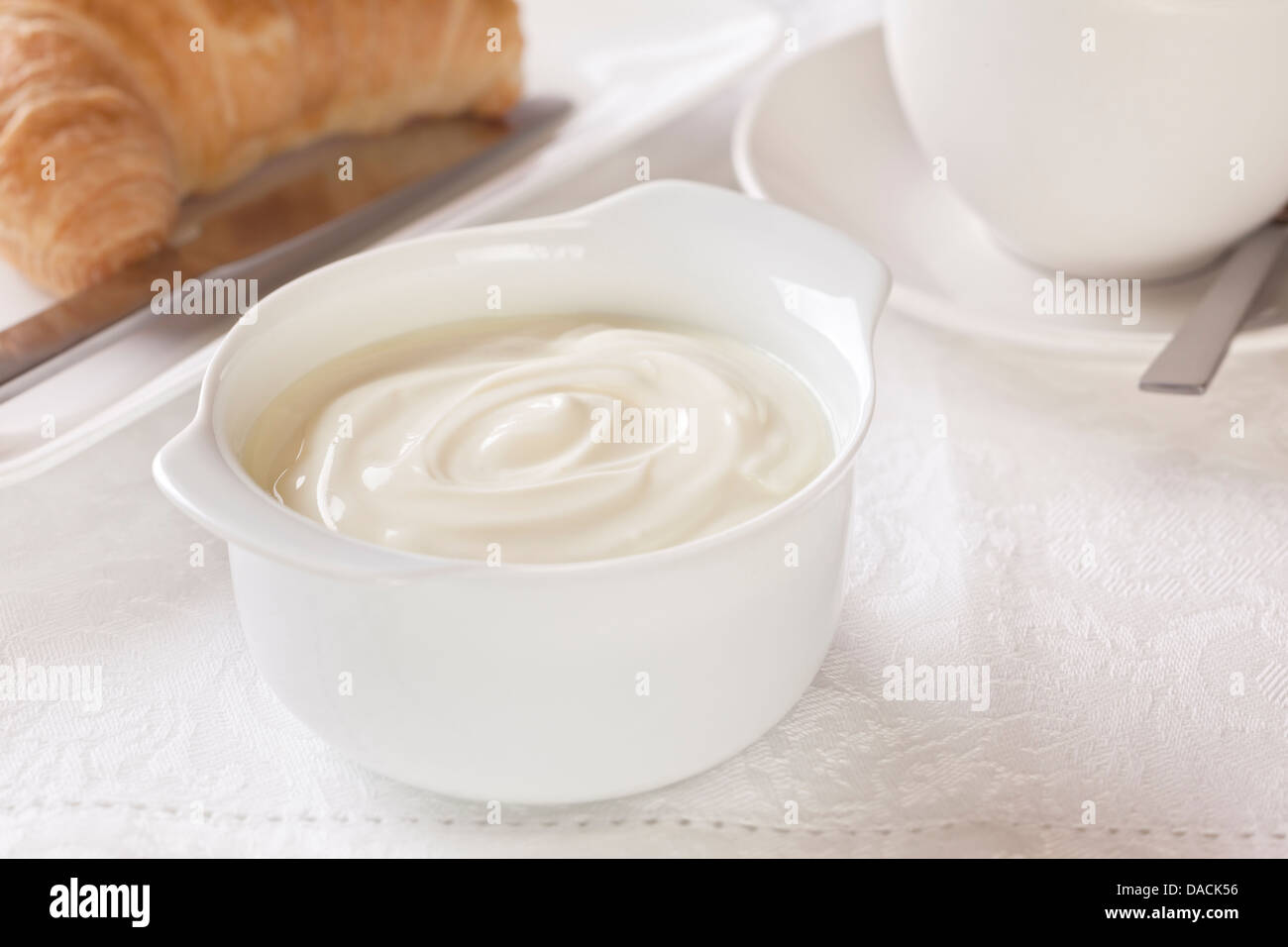 Joghurt Frühstück - Schüssel mit Joghurt zum Frühstück mit Kaffee und Croissant. Stockfoto