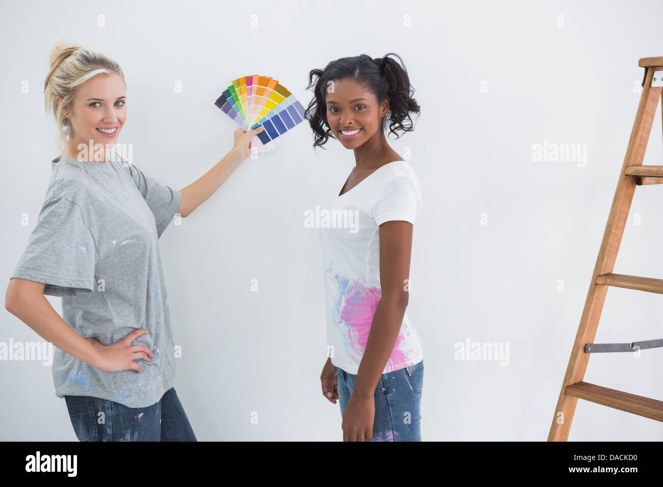 Mitbewohner Kommissionierung Farbe für leere Wand und lächelt in die Kamera Stockfoto