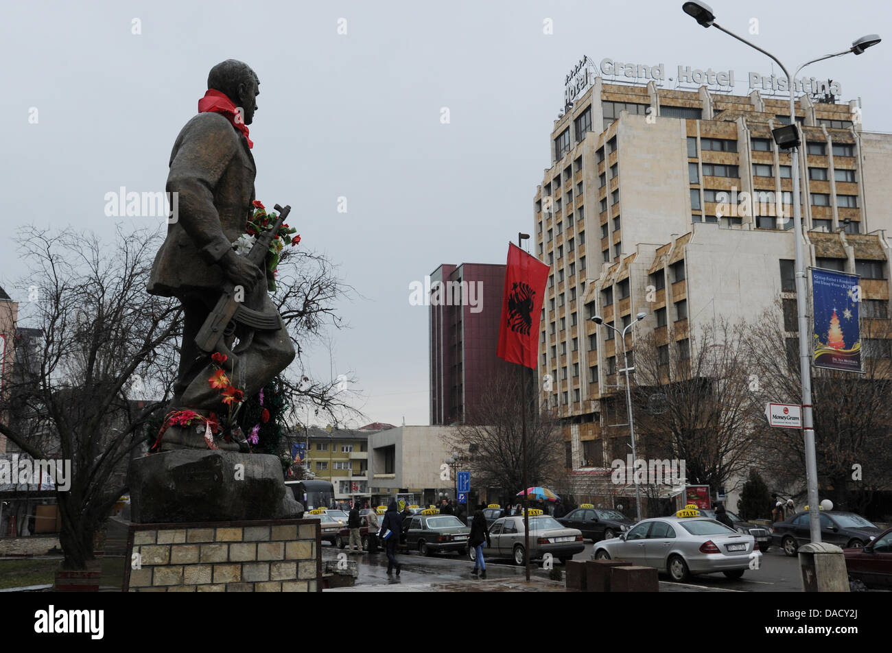Das Denkmal für Zahir Pajaziti Blumen neben der albanischen Flagge (M) vor dem Grand Hotel Pristina im Boulevard Mutter Theresa (Nena Tereza) in Pristina, Kosovo, 20. Dezember 2011 ziert. Monument war ein Kommandeur der Befreiungsarmee des Kosovo. Foto: Jens Kalaene Stockfoto