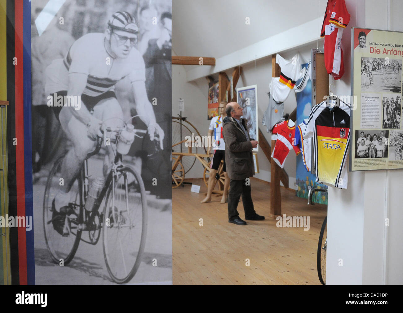 Ein Besucher beobachtet Exponate neben einem Bild des Radsports Legende