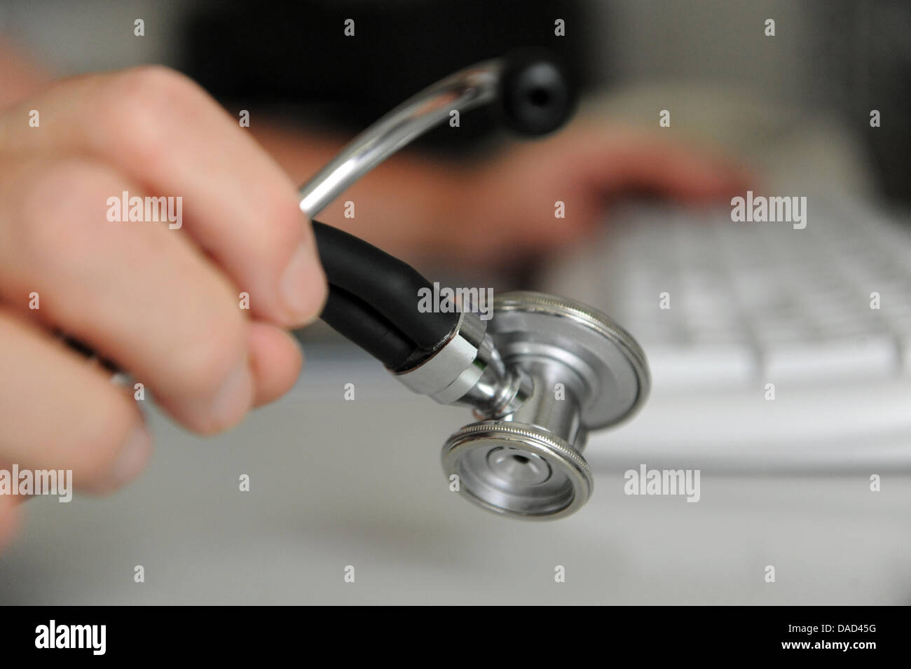 (Dpa-Datei) - ein Datei-Bild vom 25. Mai 2010 zeigt einen Arzt mit einem Stethoskop in den Händen beim Sitzen am Computer in einer Arztpraxis in Deizisau, Deutschland. Deutschlands Ärzte vermuten, dass unterschiedliche Ärzte aus verschiedenen Orten Patienten in den ländlichen Gebieten behandelt um den Mangel an Ärzten auf dem Land zu decken. Foto: Marijan Murat Stockfoto