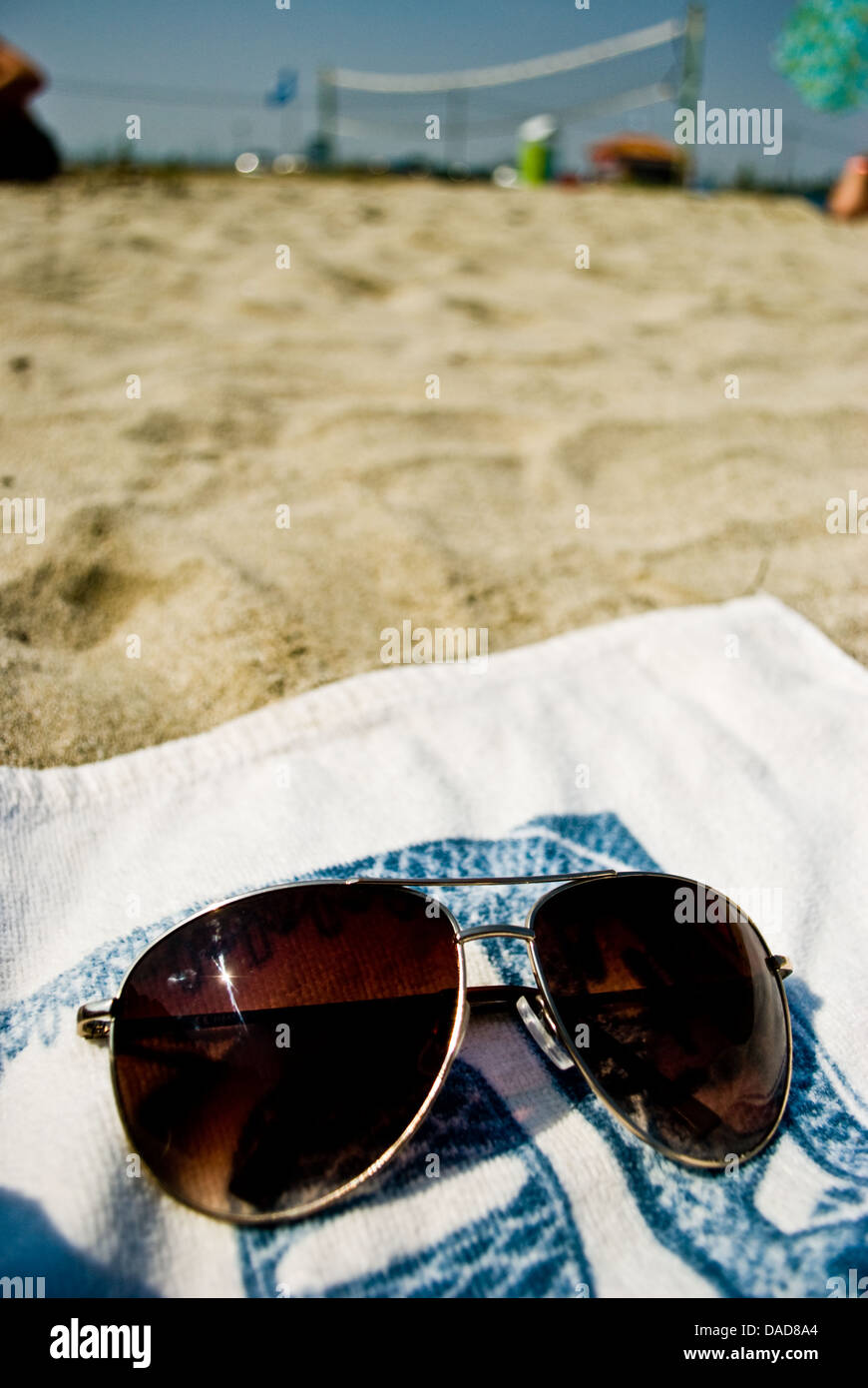 Sonnenbrille auf dem Strandhandtuch unter den Sand als Ferien-Konzept Stockfoto