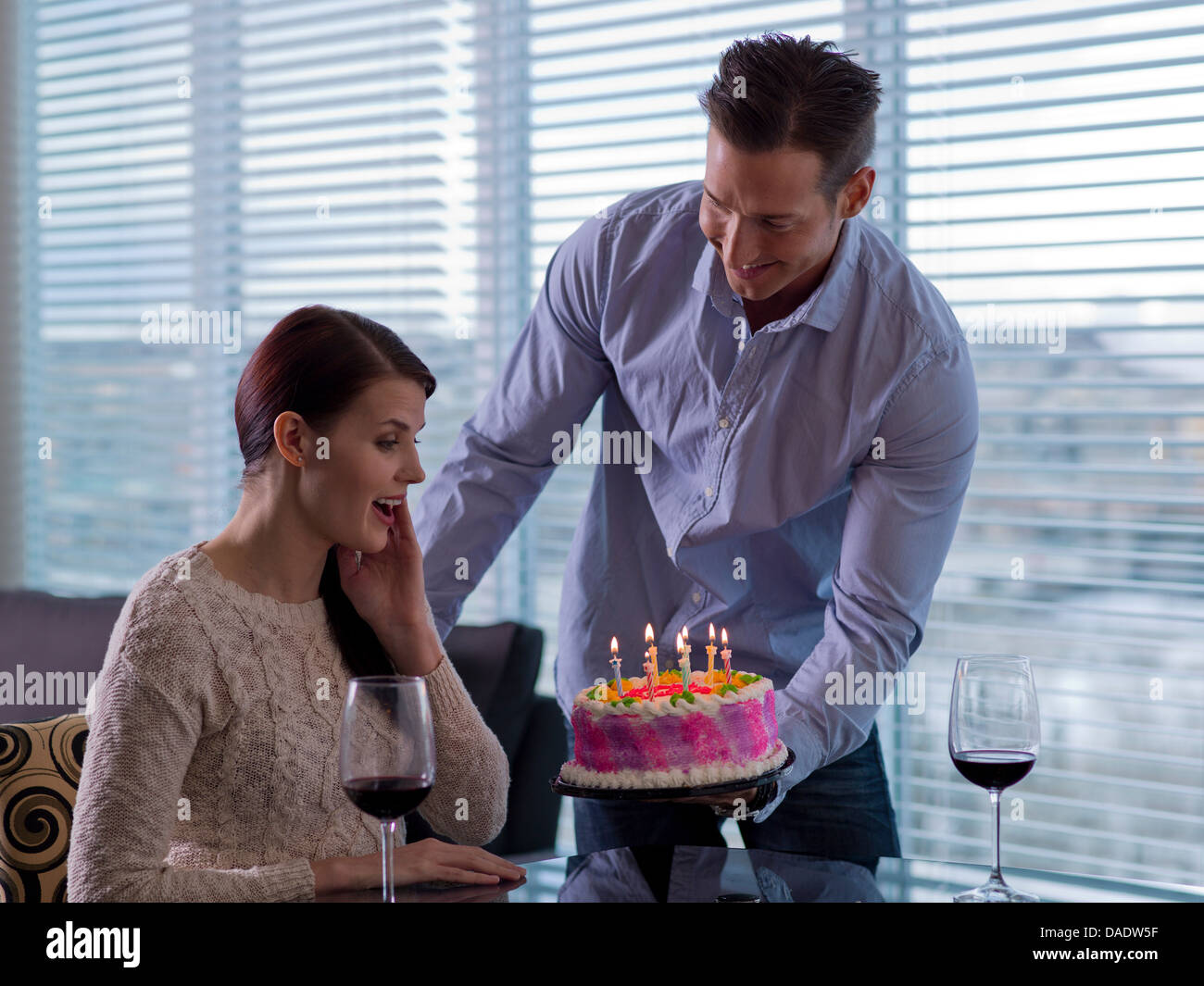 Mitte erwachsenen Mannes geben junge Frau Geburtstagstorte Stockfoto