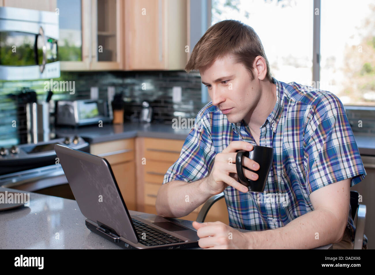 Mitte erwachsener Mann mit Laptop in der Küche Stockfoto