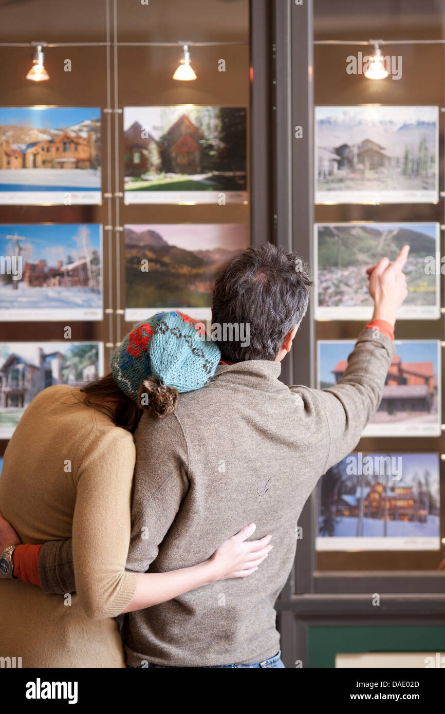 Paar auf der Suche auf Fotos im Fenster "Reisebüros" Rückansicht Stockfoto