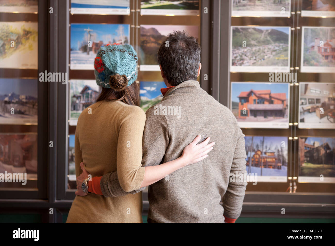 Paar auf der Suche auf Fotos im Fenster "Reisebüros" Rückansicht Stockfoto