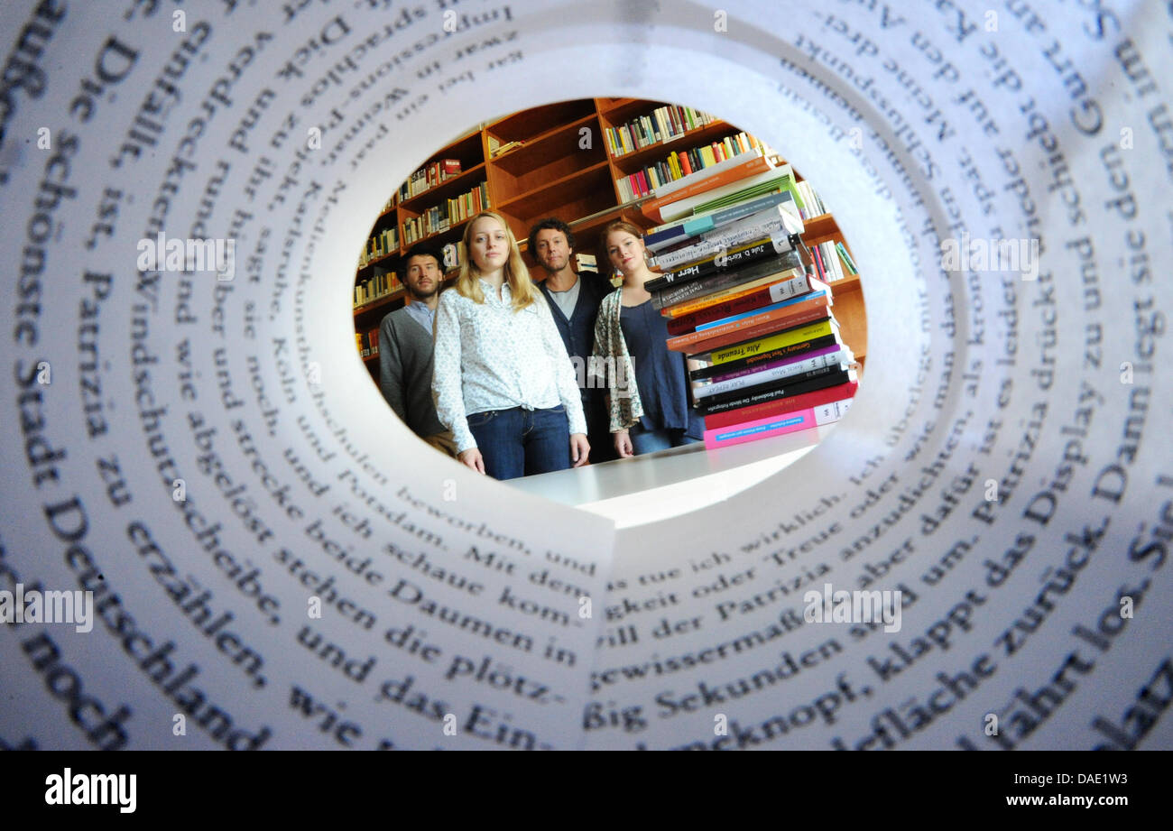 Schüler Marco Lehmbeck (L-R) und Alina Herbig, Assistent Thomas Klupp und Studentin Joanna von Graefe, Studenten der Creative Writing an der Universität Hildesheim, schauen Sie durch einen aufgerollten Seite des Thomas Klupps "Paradiso" in Hildesheim, Deutschland, 19. Oktober 2011. Zwölf Jahre nach seiner Eröffnung hat das Institut Universität große es geschafft, einen Platz in der deutschen Literatur zu sichern Stockfoto