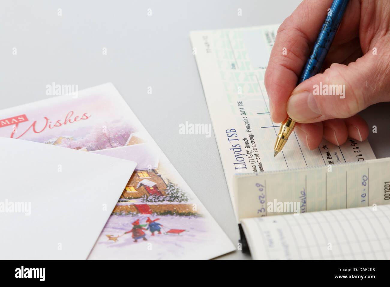 Ältere weibliche Dame Rentner Schreiben einer Lloyds Bank prüfen als Geschenk in eine Weihnachtskarte. England, Großbritannien, Großbritannien. Stockfoto