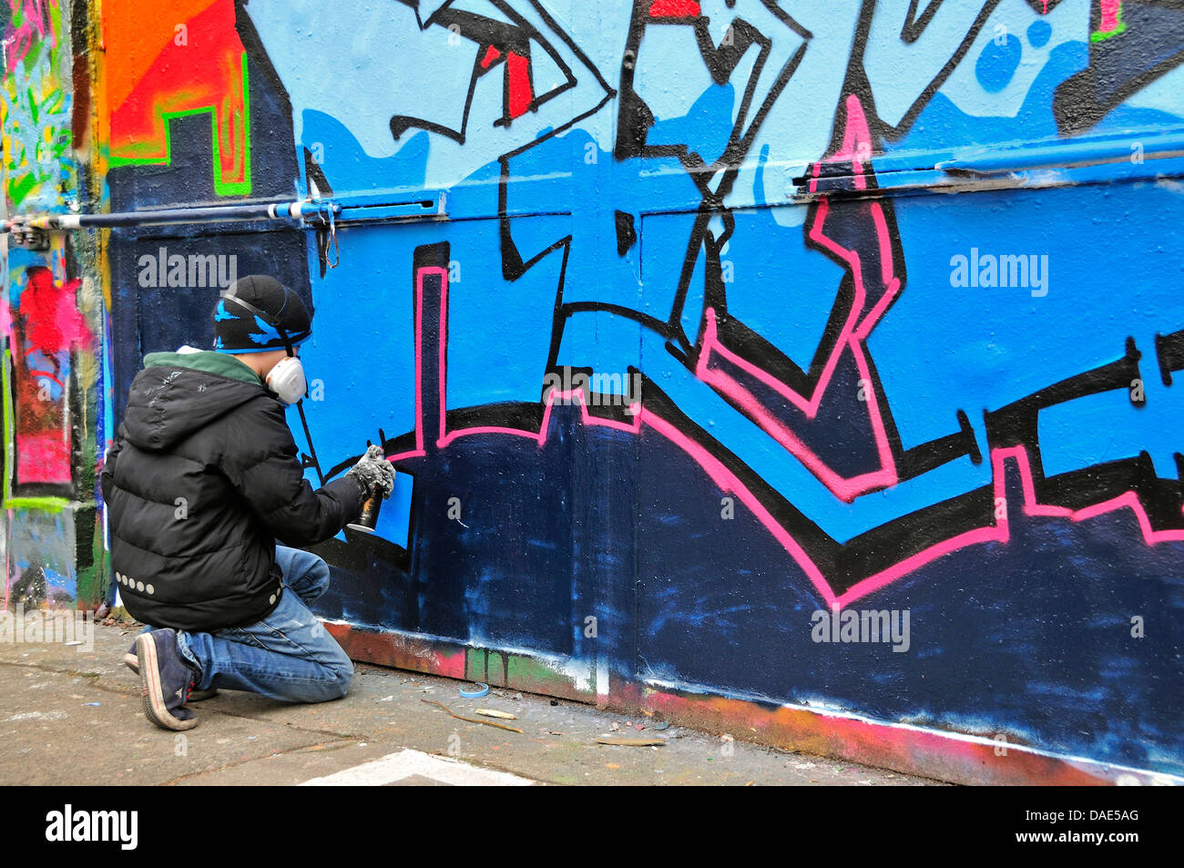 Eleven-Year-Old Boy Spritzen an Graffitiwand, Deutschland, Nordrhein-Westfalen, Köln Stockfoto