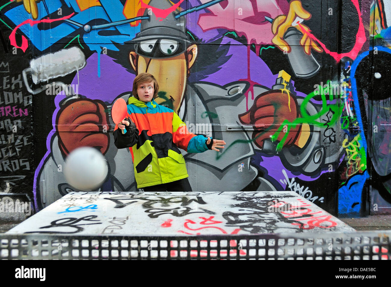 zwölf Jahre alten Jungen Tischtennis vor Graffitiwand, Deutschland, Nordrhein-Westfalen, Köln Stockfoto