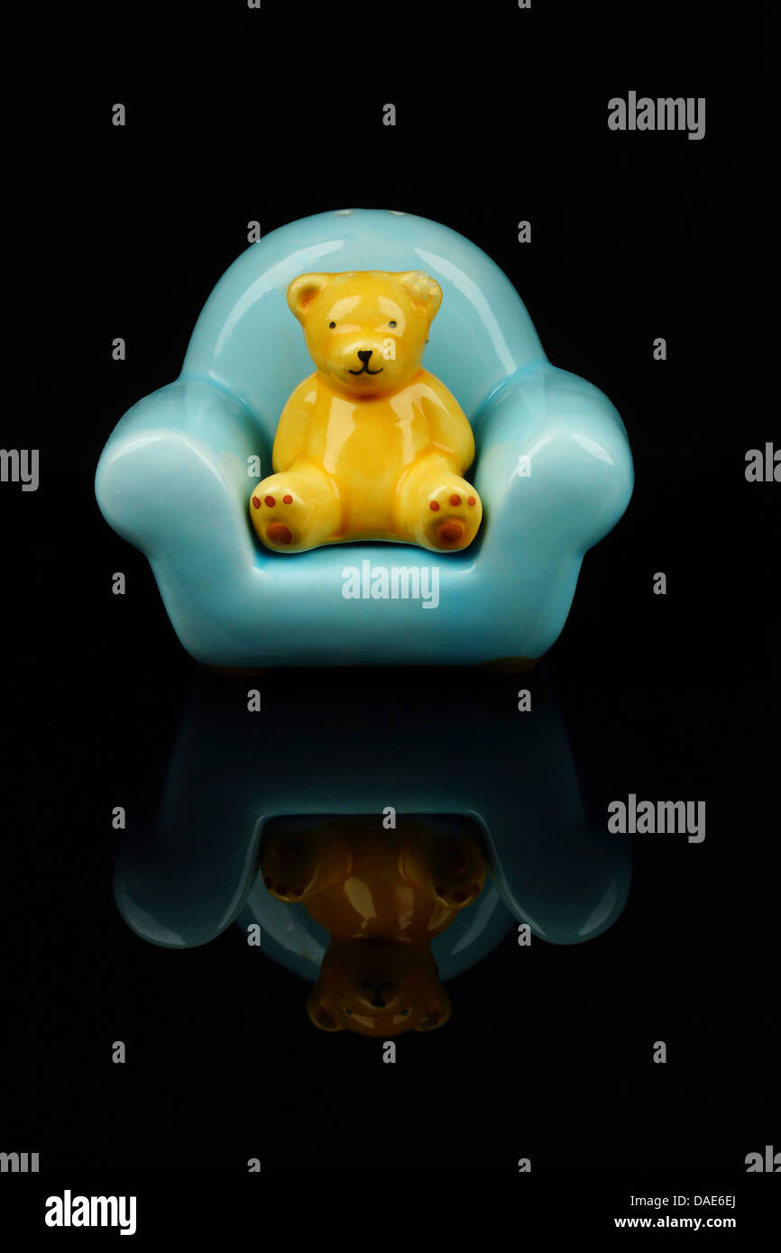 Figur der Teddybär auf Stuhl vor schwarzem Hintergrund, Nahaufnahme Stockfoto