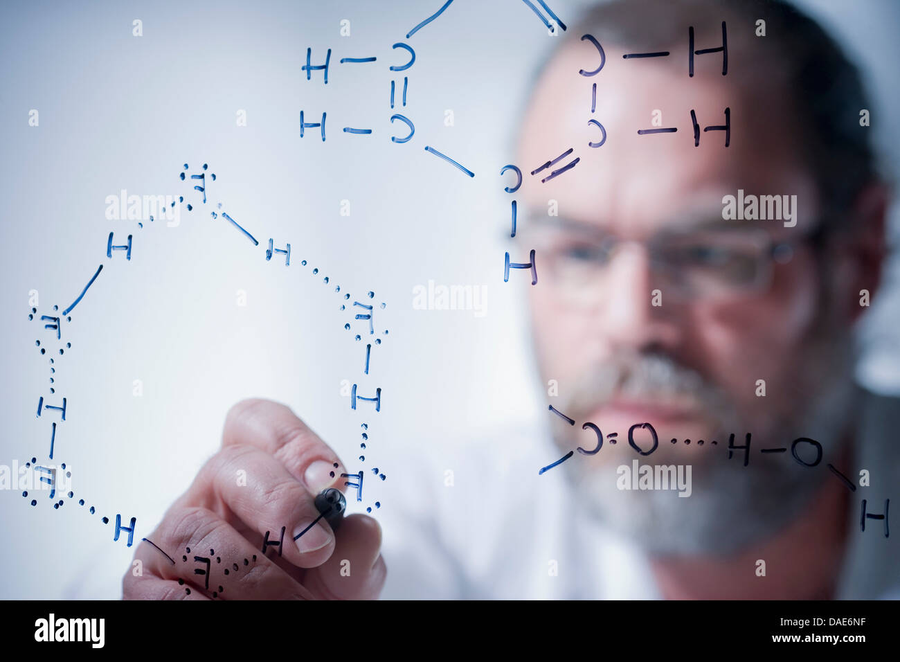 Wissenschaftler schreiben wissenschaftliche Symbole auf Glas Stockfoto
