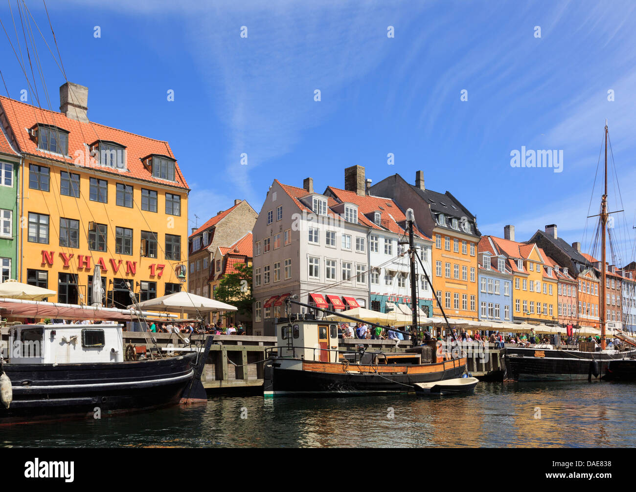 Alte hölzerne Boote vertäut am Kanal von bunten 17. Jahrhundert Gebäude am Wasser im Hafen von Nyhavn, Kopenhagen, Dänemark Stockfoto