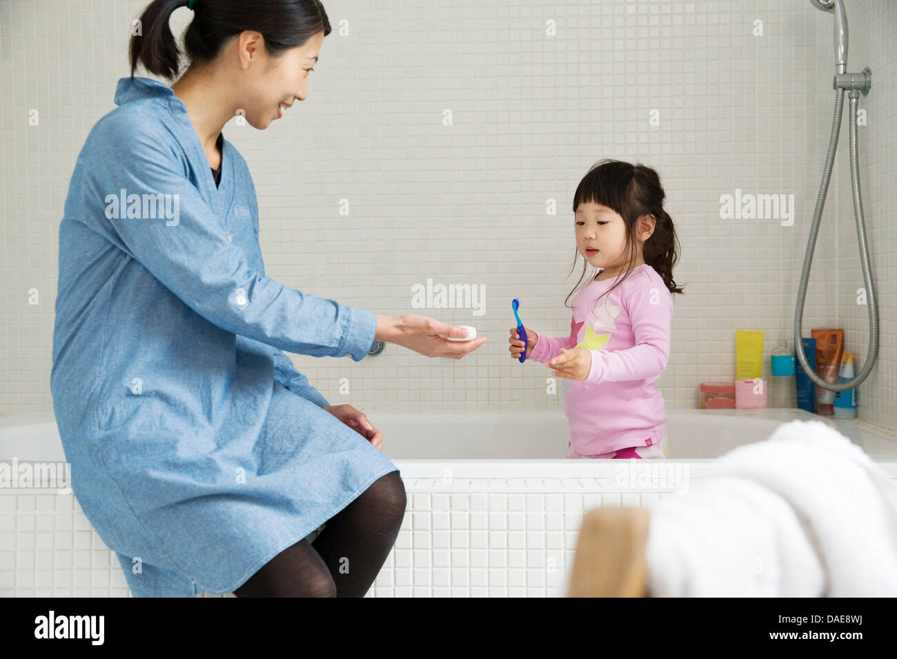 Mutter mit weiblichen Kleinkind stehen im Bad mit Zahnbürste Stockfoto