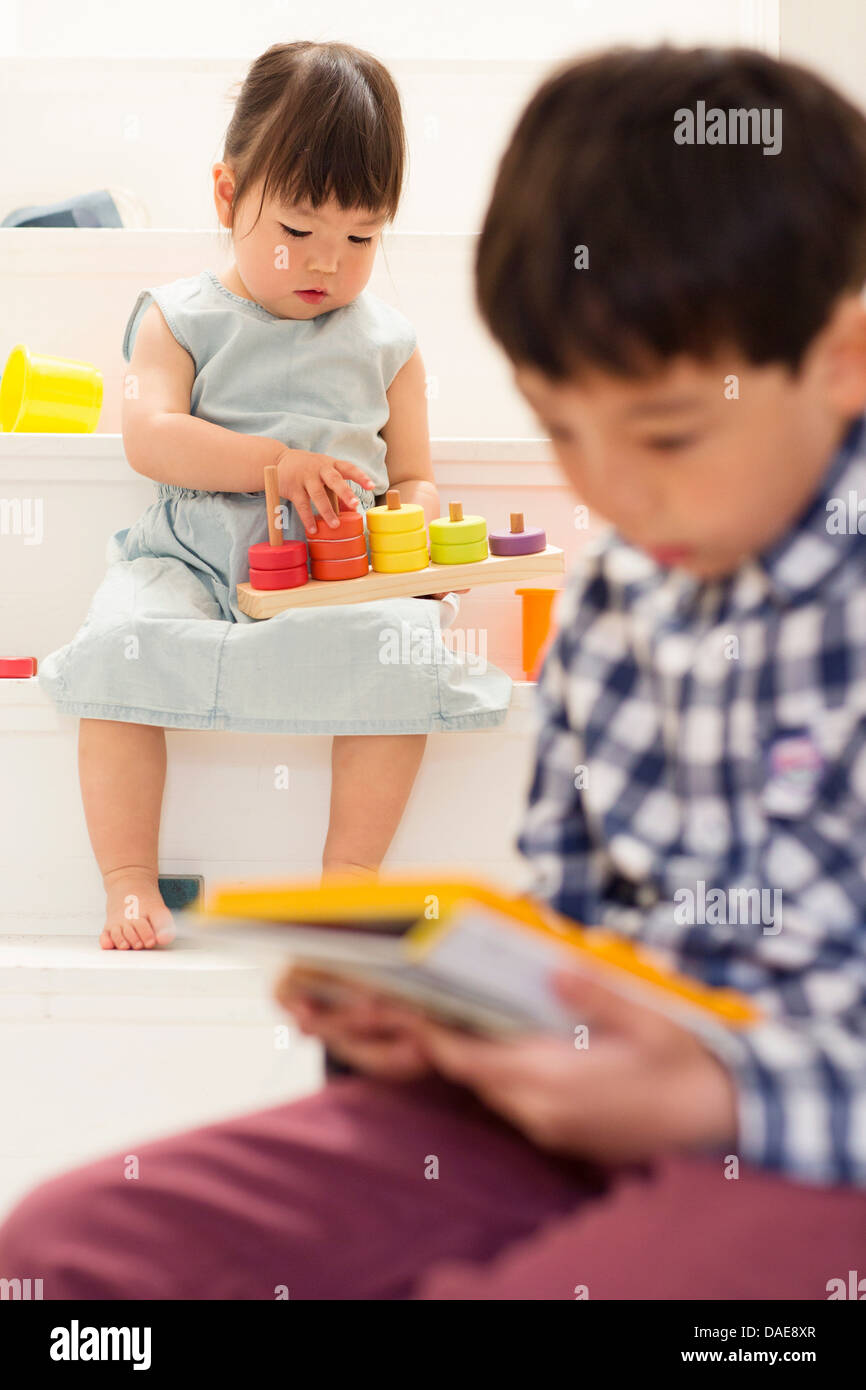 Bruder und Schwester spielt mit Spielzeug auf Treppe Stockfoto