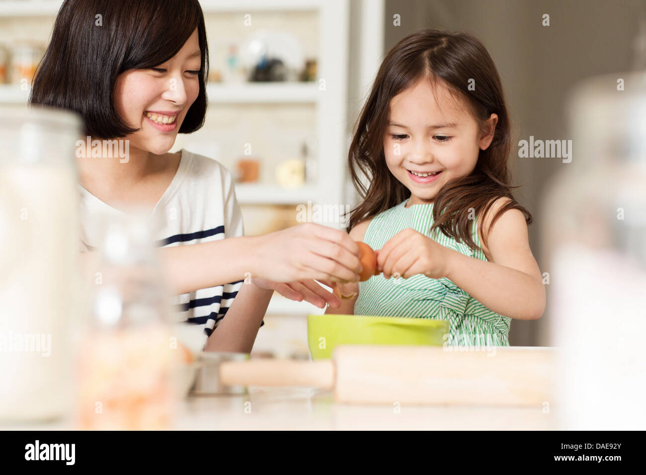 Mutter und junge Tochter knacken Ei in eine Rührschüssel geben Stockfoto