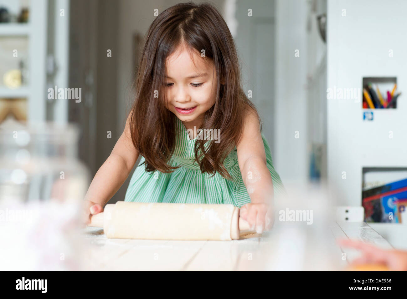 Junges Mädchen ausrollen Teig auf Küchentisch Stockfoto