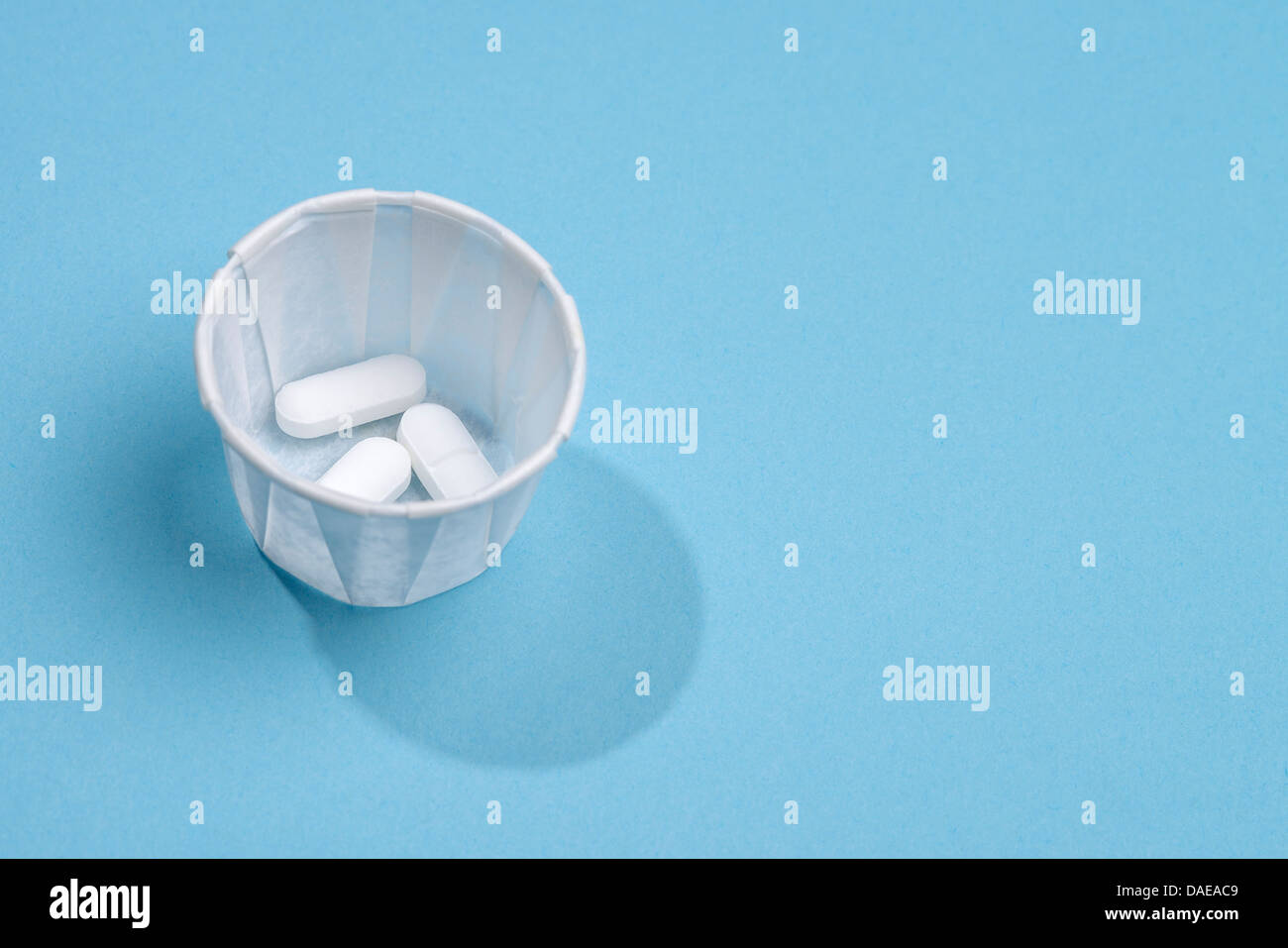 Weiße Tabletten in eine Einweg-Papier Verzicht auf Tasse Stockfoto