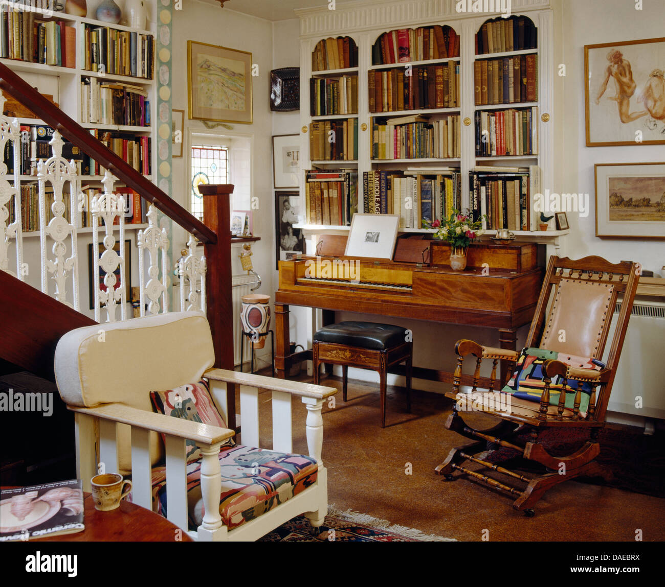 Antike Spinett unten im Ferienhaus Wohnzimmer mit Edwardian Schaukelstuhl Bücherregal montiert und lackiert Holz Sessel Stockfoto