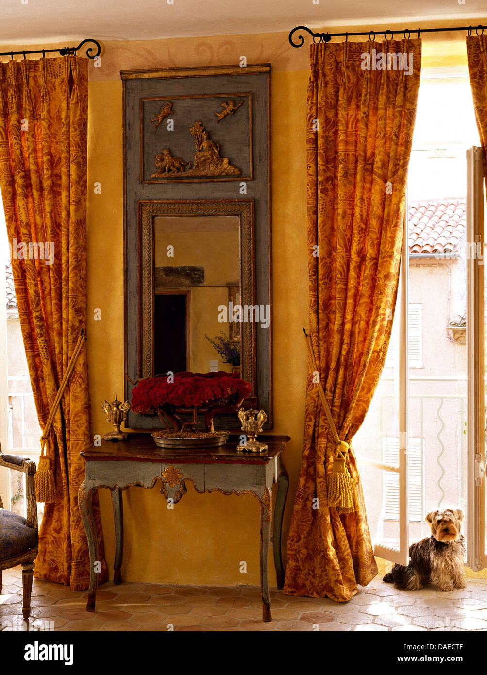 Grau lackiert, antiker Spiegel und Konsole Tisch zwischen französische  Fenster mit gemusterten gelb gemusterten Gardinen im Wohnzimmer  Stockfotografie - Alamy