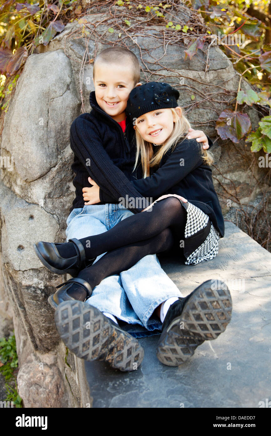 Lächelnden jungen und Mädchen sitzen auf steinernen Sims, Porträt Stockfoto