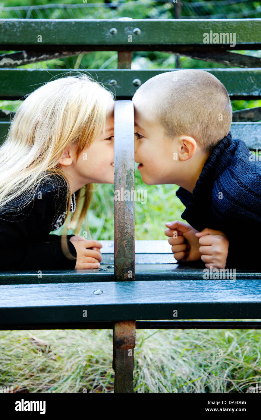 Jungen und Mädchen sahen einander unter Park Bench Armlehne Stockfoto