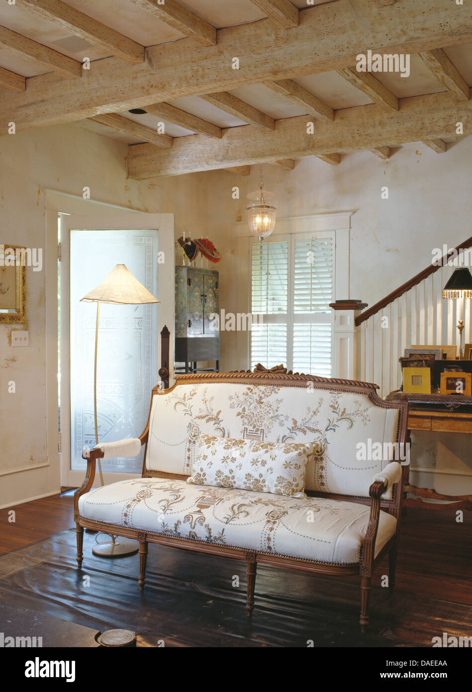 Französische gerahmte Holzsofa in weißen Land Wohnzimmer mit beleuchteten Lampe und Kalk gewaschen Balken Stockfoto