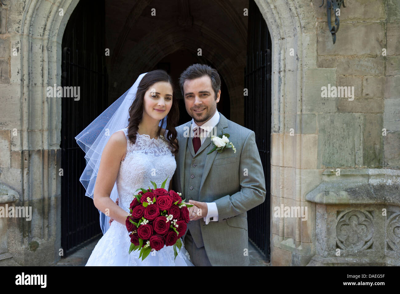 Braut & Bräutigam WHITE WEDDING BOUQUET Attraktive glückliche junge Kirche traditionelle Braut und Bräutigam Just married außerhalb der gotischen Kirche Tür Stockfoto