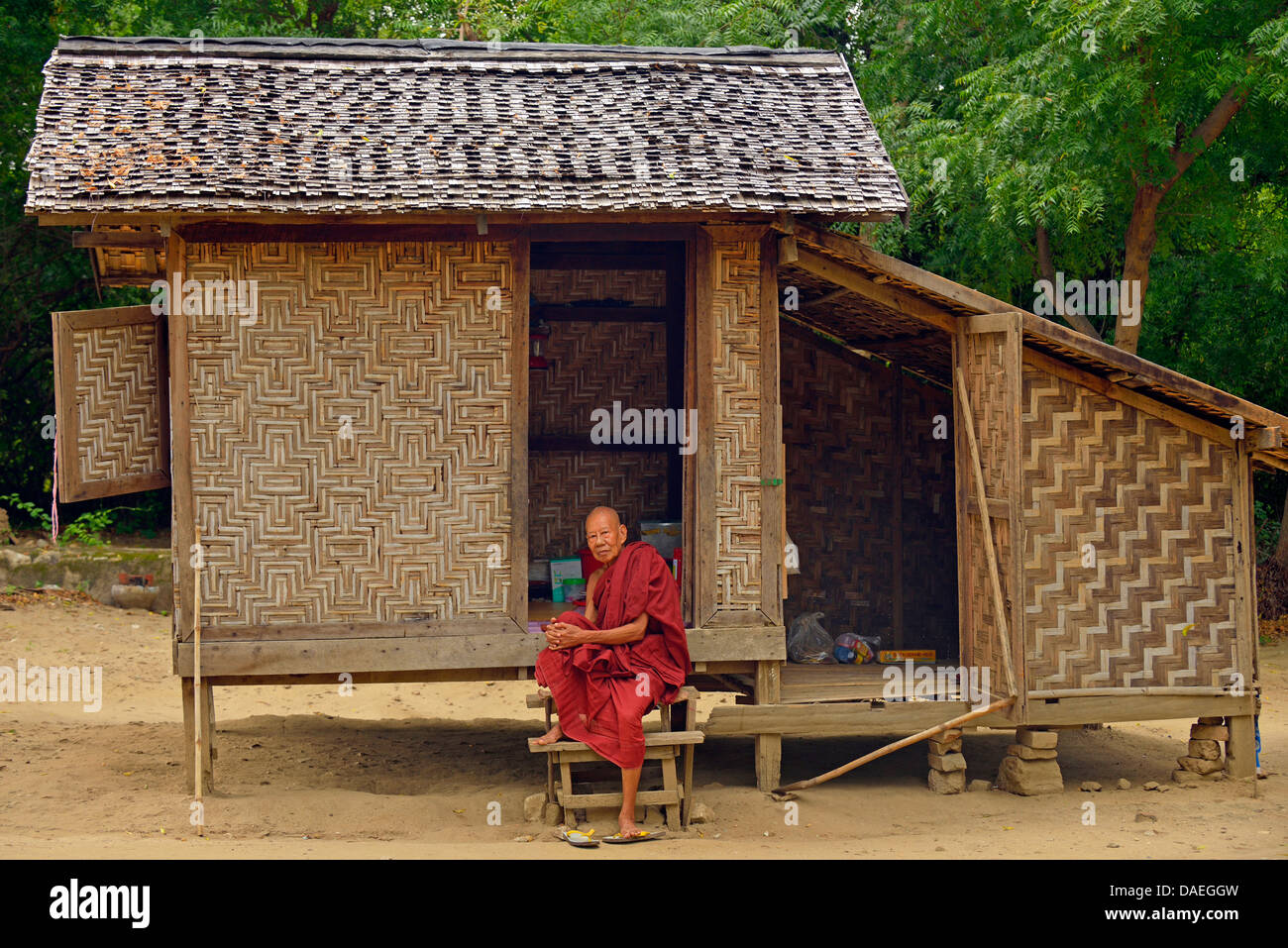 alten Mönch auf der Treppe von seinem bescheidenen Holzhaus, Burma, Mandalay Stockfoto