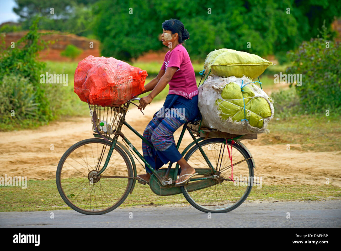 Frau, die Transport von drei schwere Säcke auf dem Fahrrad, Burma Stockfoto