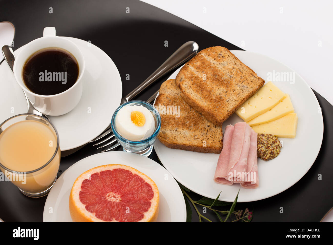 Frühstück mit Toast, Schinken, Käse, Ei, Grapefruit, Saft und Kaffee. Stockfoto