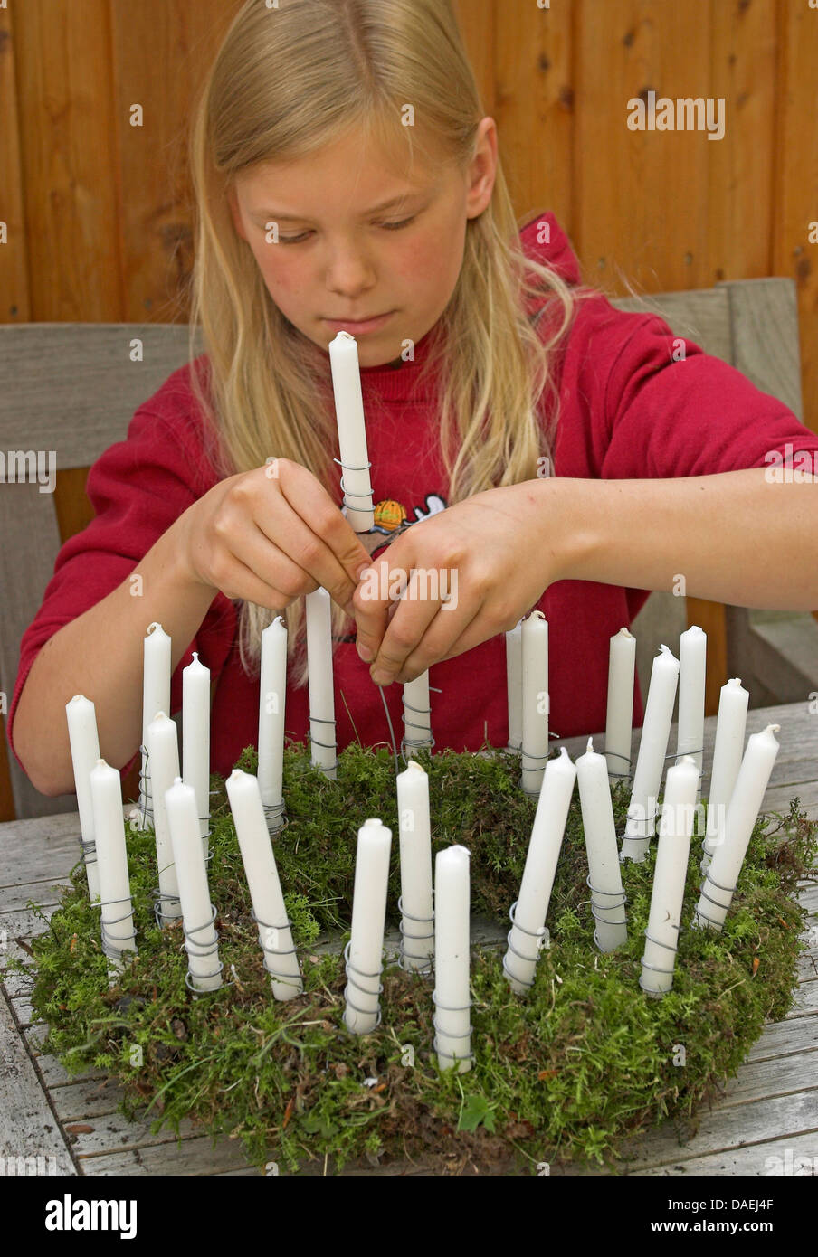 Mädchen kleben Kerzen auf einem Kranz für die Adventszeit, Deutschland Stockfoto