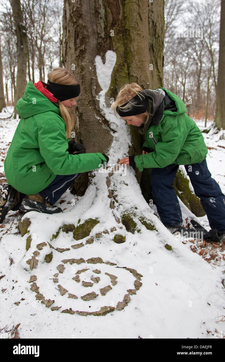 Kinder haften Rindenstückchen als Spirale in den Schnee, Deutschland Stockfoto