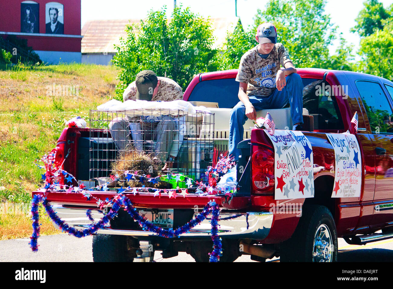 Zwei Männer sitzen im Bett von verzierten roten Pickup-Truck zusammen mit erbeuteten wilde Stachelschwein an jährlichen 4. Juli Parade im Rat, ID Stockfoto