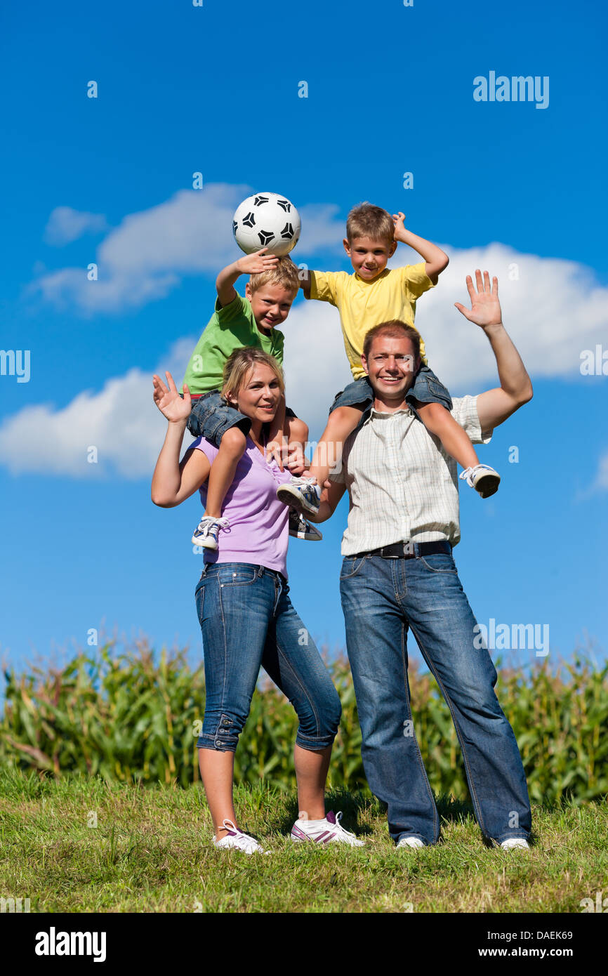 Familie mit zwei kleinen Jungen spielen in den Rasen auf einer Sommerwiese - sie haben einen Fußball Stockfoto