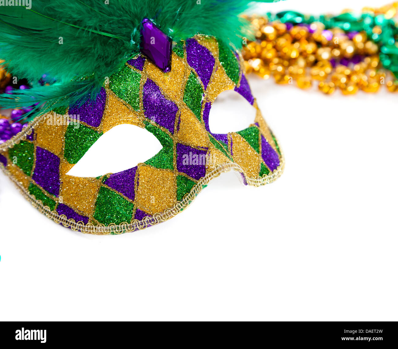 Eine lila, gold und grün Karneval Maske und Perlen auf weiß Stockfoto
