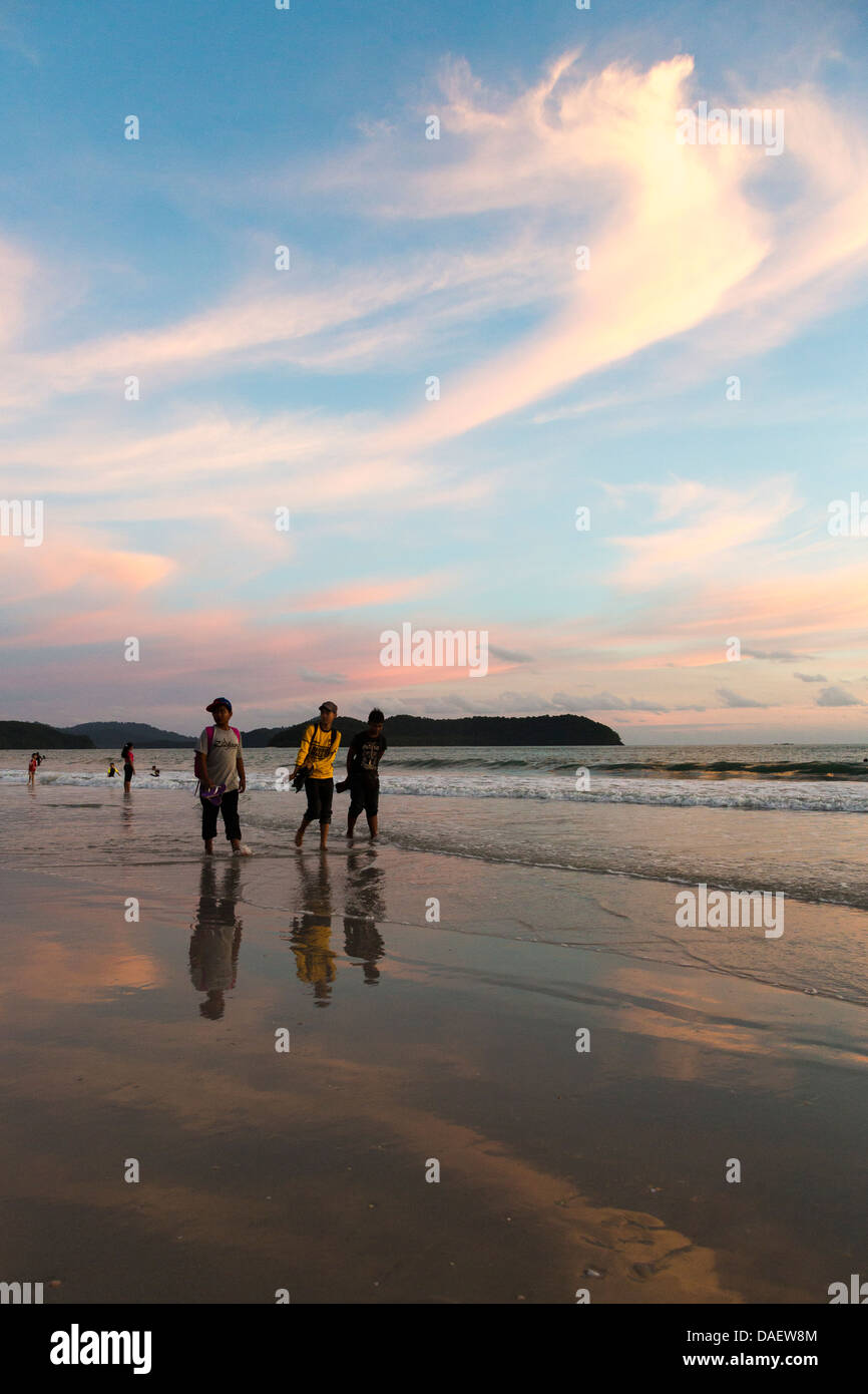 Dir asiatische Touristen zu Fuß am Pantai Cenang Strand in Langkawi während des Sonnenuntergangs, Malayisa Stockfoto