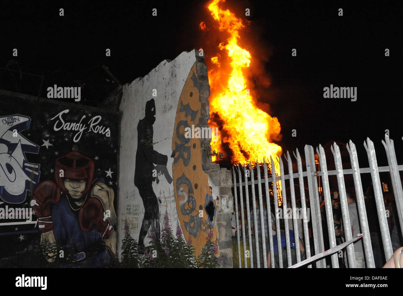 Belfast, Nordirland. 11. Juli 2013. Am 11. Juli werden standhaft protestantischen Gebieten "Elfte Nacht" Freudenfeuer angezündet. Viele sind massive Konstruktionen aus Holz Paletten, alte Sofas und Gummireifen, garniert mit irischen Fahnen oder Bildnisse von pro-Nationalist zahlen. Lagerfeuer Architekten Schlacht es sehen, wer der größte aufbauen kann und Verschiebungen der junge Wächter sicherzustellen, dass die rivalisierende Bauherren nicht brennbarer Beute stehlen. Um Mitternacht die Freudenfeuer angezündet werden, und diese wütenden Infernos lodernden quer durch die Stadt zu sehen. Im Bild: Sandy Row Lagerfeuer. Bildnachweis: Andrew Chittock/Alamy Live-Nachrichten Stockfoto