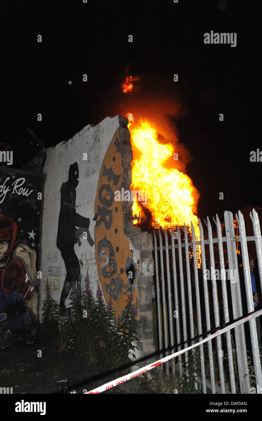 Belfast, Nordirland. 11. Juli 2013. Am 11. Juli werden standhaft protestantischen Gebieten "Elfte Nacht" Freudenfeuer angezündet. Viele sind massive Konstruktionen aus Holz Paletten, alte Sofas und Gummireifen, garniert mit irischen Fahnen oder Bildnisse von pro-Nationalist zahlen. Lagerfeuer Architekten Schlacht es sehen, wer der größte aufbauen kann und Verschiebungen der junge Wächter sicherzustellen, dass die rivalisierende Bauherren nicht brennbarer Beute stehlen. Um Mitternacht die Freudenfeuer angezündet werden, und diese wütenden Infernos lodernden quer durch die Stadt zu sehen. Im Bild: Sandy Row Lagerfeuer. Bildnachweis: Andrew Chittock/Alamy Live-Nachrichten Stockfoto
