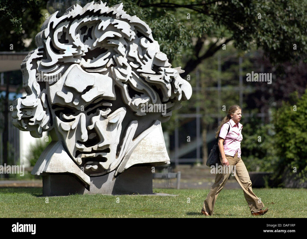 (Dpa Datei) - eine Archiv Bild, datiert 11. August 2004, zeigt eine Frau, vorbei an einer Skulptur, die Darstellung der deutschen Komponisten Ludwig van Beethoven des deutschen Künstlers Klaus Kammerichs in Bonn, Deutschland. Nach umfangreichen öffentlichen Debatte hat der Stadtrat der Stadt Bonn nun entschieden, für den Bau der neuen Konzerthalle, das Beethoven Festspielhaus in Bonn. Foto: Felix Heyder Stockfoto