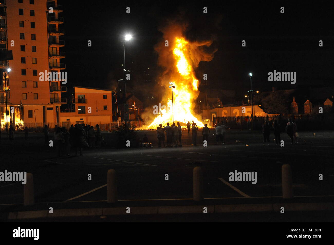 Belfast, Nordirland. 11. Juli 2013. Am 11. Juli werden standhaft protestantischen Gebieten "Elfte Nacht" Freudenfeuer angezündet. Viele sind massive Konstruktionen aus Holz Paletten, alte Sofas und Gummireifen, garniert mit irischen Fahnen oder Bildnisse von pro-Nationalist zahlen. Lagerfeuer Architekten Schlacht es sehen, wer der größte aufbauen kann und Verschiebungen der junge Wächter sicherzustellen, dass die rivalisierende Bauherren nicht brennbarer Beute stehlen. Um Mitternacht die Freudenfeuer angezündet werden, und diese wütenden Infernos lodernden quer durch die Stadt zu sehen. Im Bild: Sandy Row Lagerfeuer. Bildnachweis: Andrew Chittock/Alamy Live-Nachrichten Stockfoto
