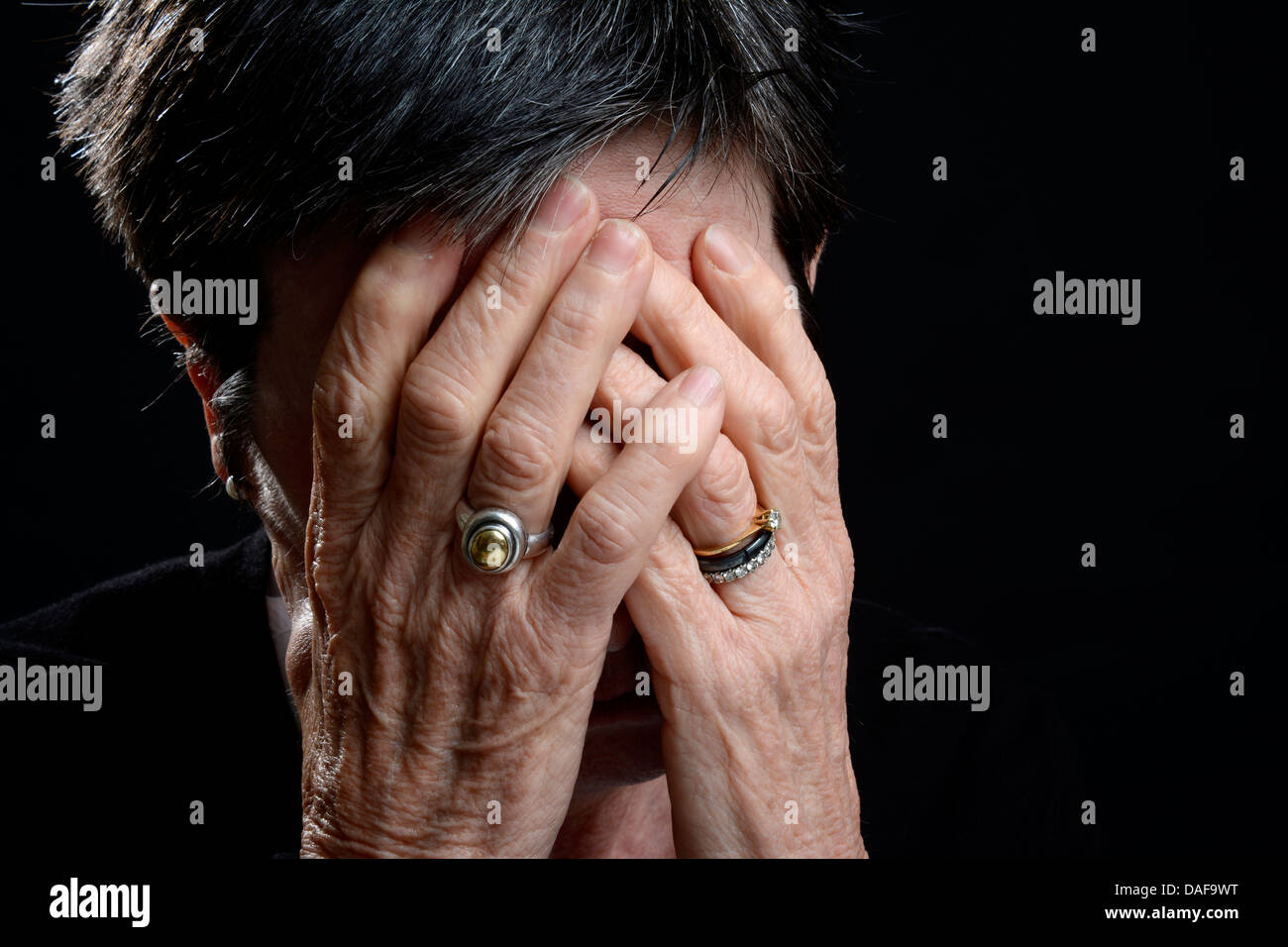 Traurige alte Frau, die ihr Gesicht mit den Händen/Weinen, psychische Gesundheit Konzept Stockfoto