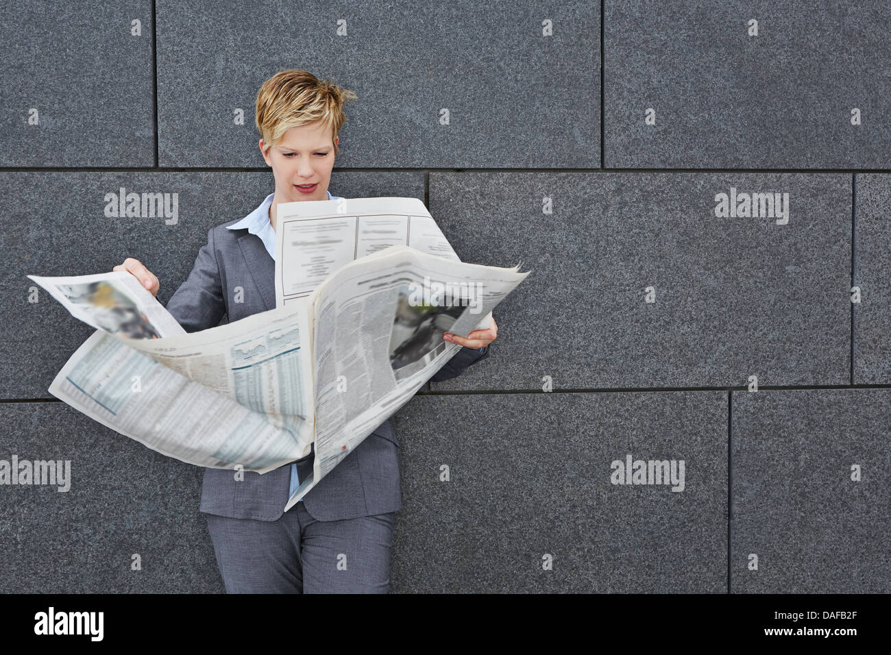Geschäftsfrau, die Lektüre einer Tageszeitung in windigem Wetter im freien Stockfoto