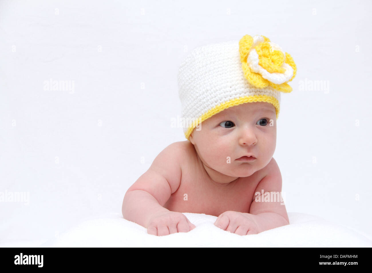 Baby mit einer weißen Mütze mit gelber Blume Stockfoto