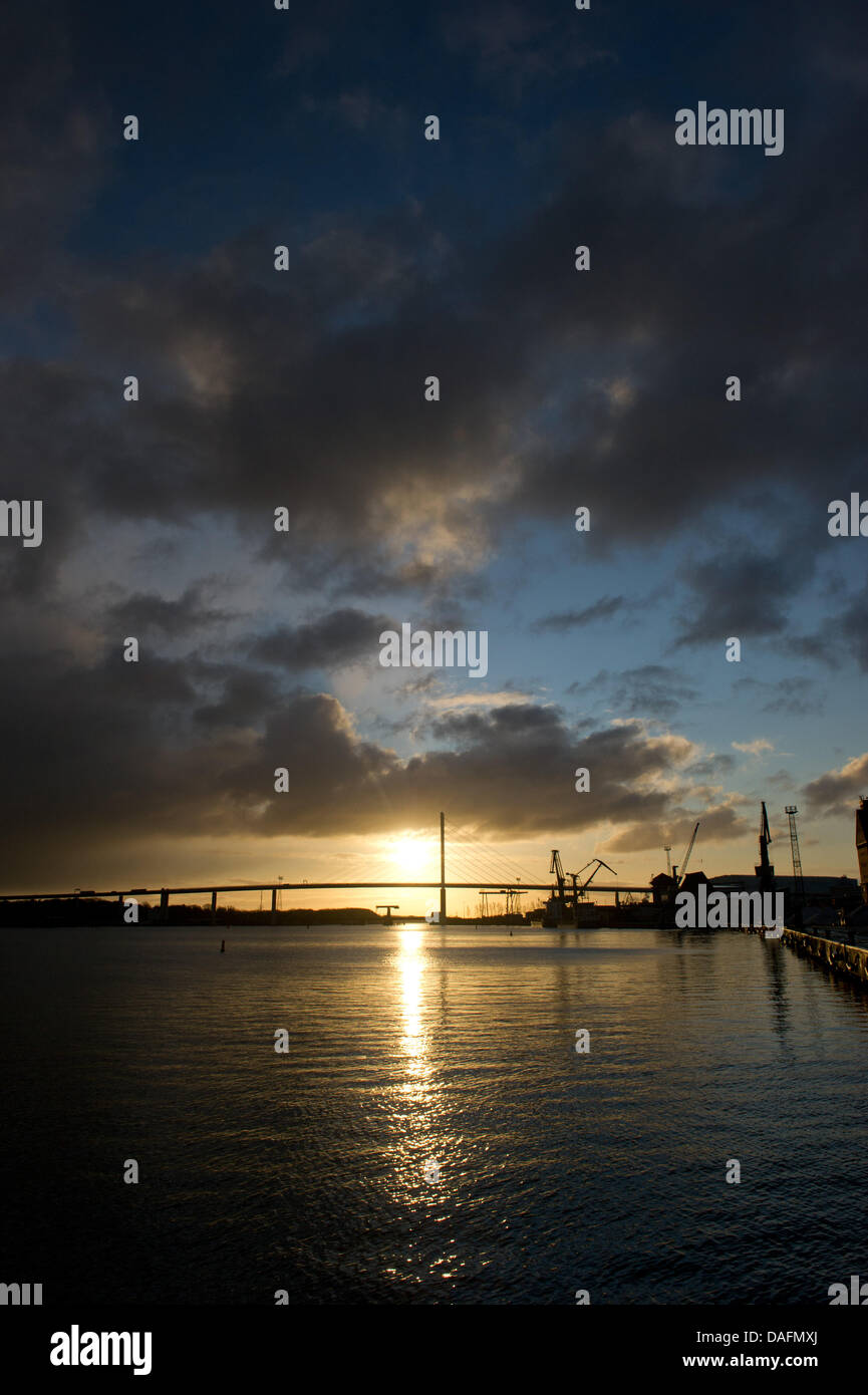 Die Sonne geht hinter der Rügen-Brücke und der Hafen von Stralsund, Deutschland, 5. Dezember 2011. Foto: Stefan Sauer Stockfoto