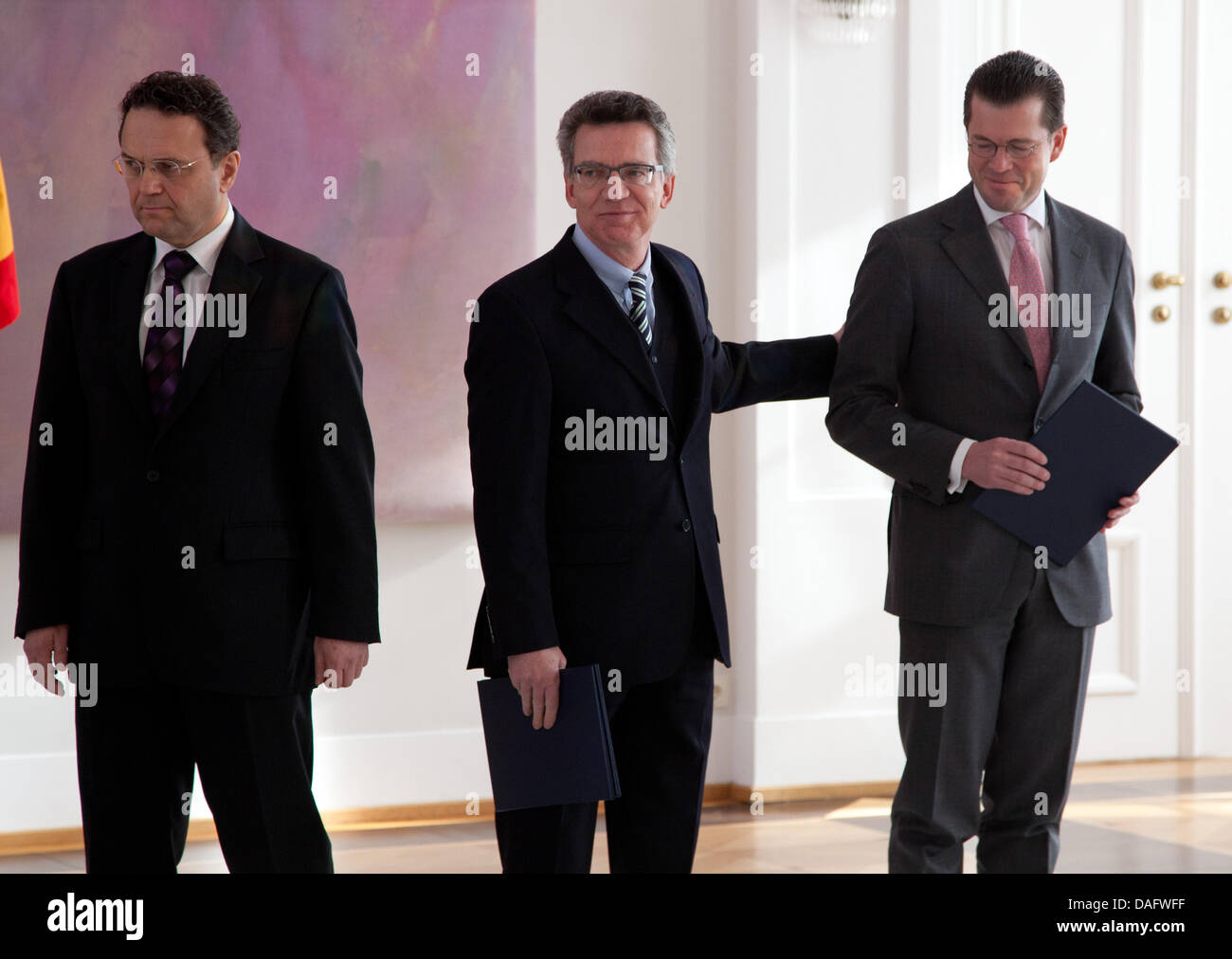 Deutschlands neue Defence Minister Thomas de Maiziere (C) tippt die Schulter von seinem Vorgänger Karl-Theodor Zu Guttenberg, während deutsche Interior Minister Hans-Peter Friedrich (L) das Schloss Bellevue in Berlin, Deutschland, 3. März 2011 verlässt. Bundespräsident Christian Wulff zuvor ernannt de Maiziere als deutsche Verteidigungsminister. Foto: HERBERT KNOSOWSKI Stockfoto